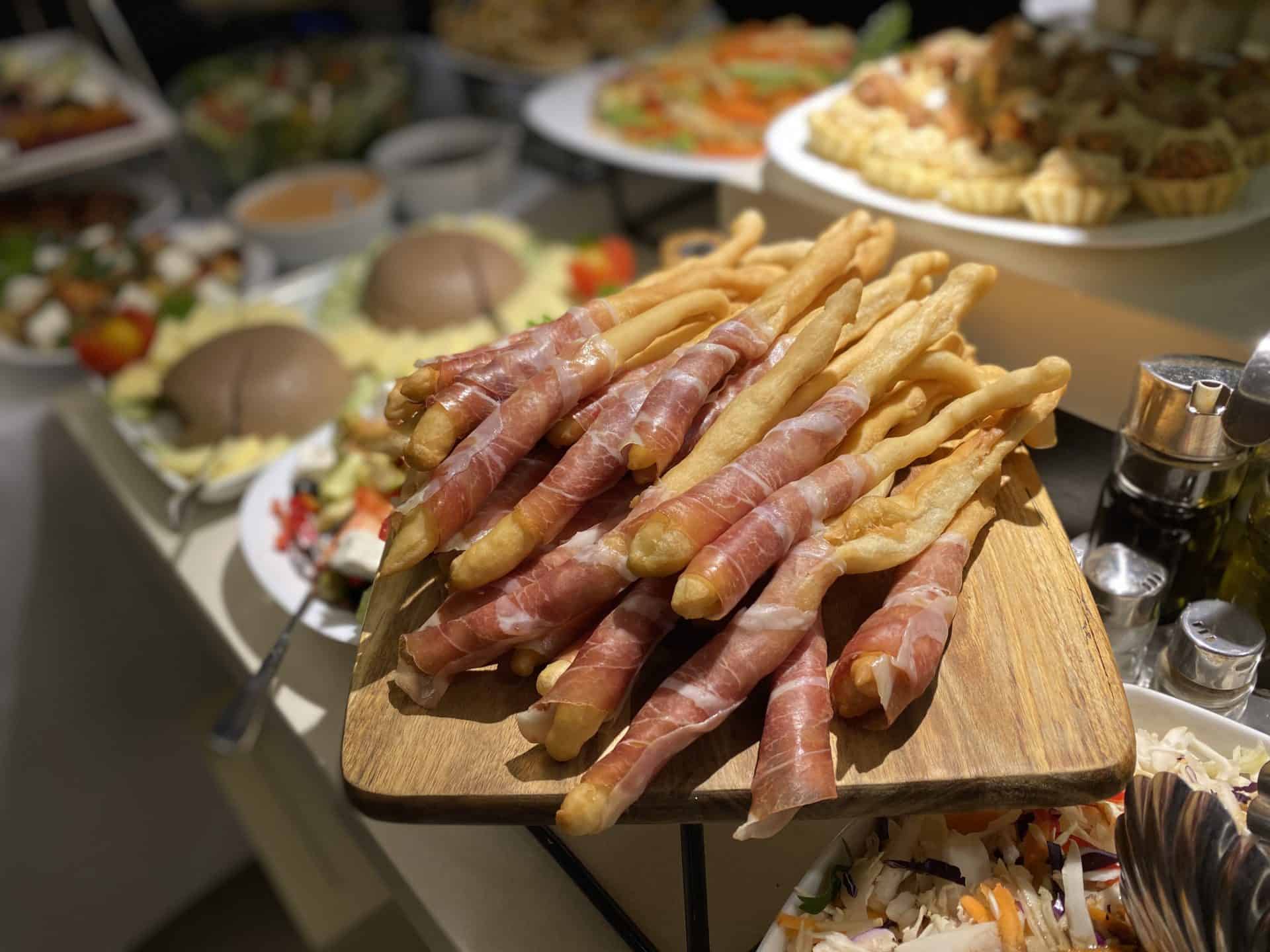 Štangle obmotane pršutom na drvenoj daski