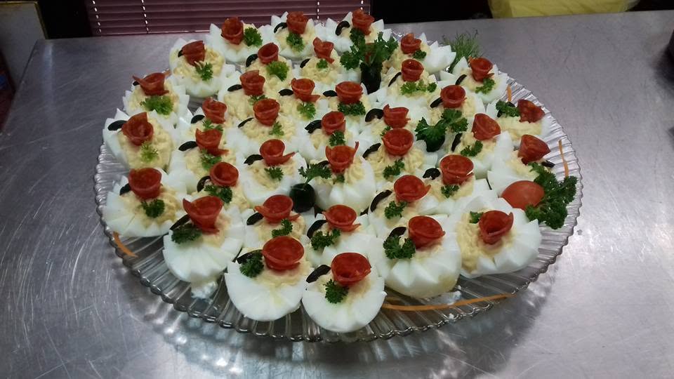 Plato punjenih jaja sa rozetama od salame, maslinama i peršunom