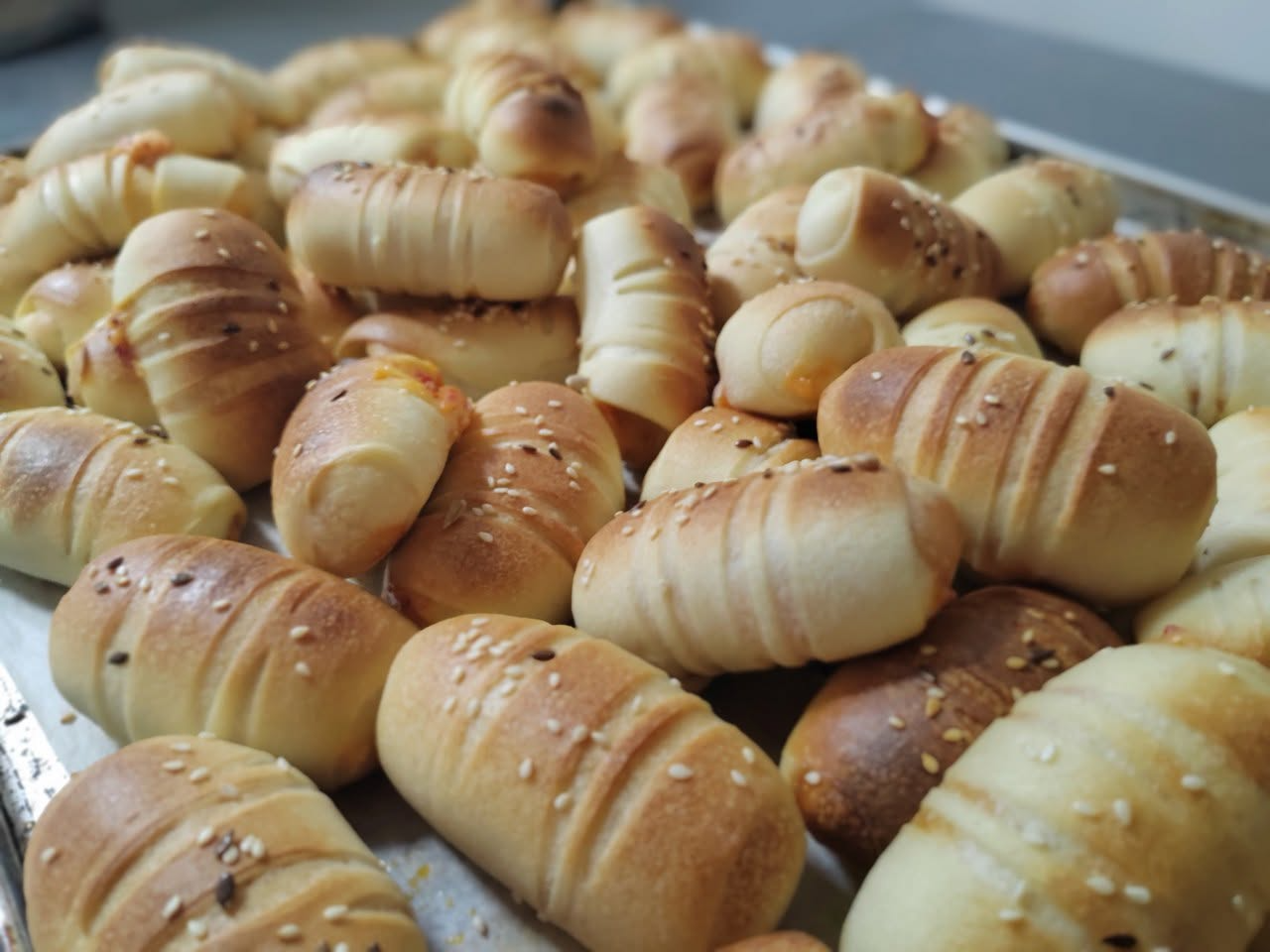 Tepsija sveže pečenih kiflica sa susamom i lanom — Fabrika kiflica
