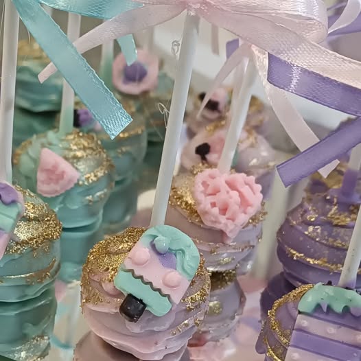 Cake pops u pastelnim bojama sa zlatnim šljokicama i mašnama