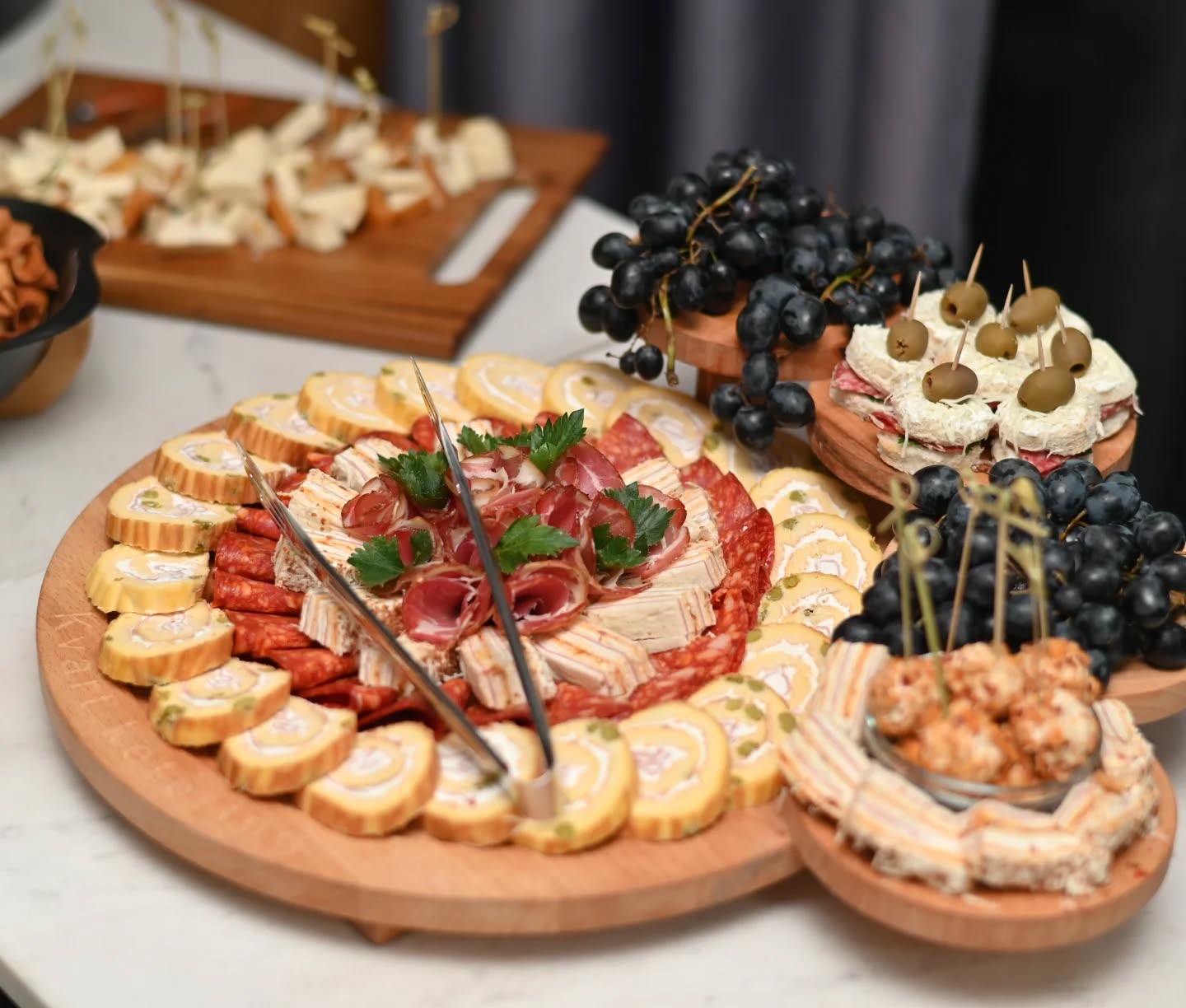Okrugli plato sa slanim rolatima, pršutom i grožđem