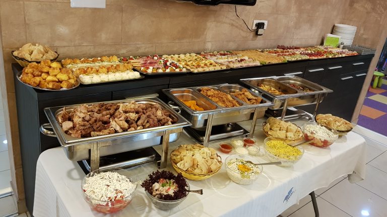 Topla jela u grejačima, salate i pecivo na dugačkom stolu