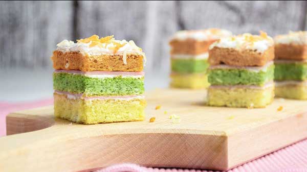 Šarene slojevite kocke sa kremom i kokosom na drvenoj dasci