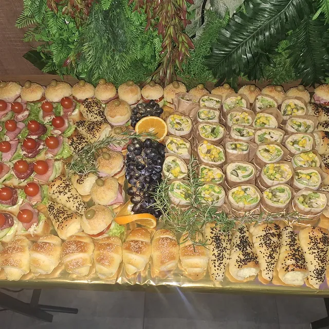 Dugački plato sa kanapeima, rolatima i pecivom, ukrašen grožđem