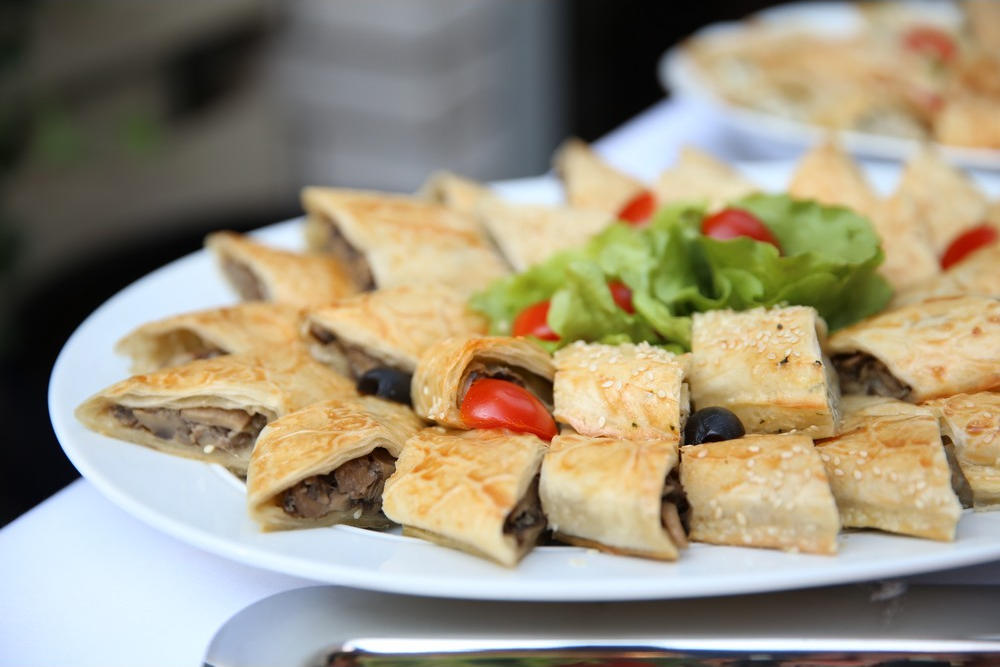 Plato sa komadima lisnatog testa punjenog mesom, uz zelenu salatu i čeri paradajz